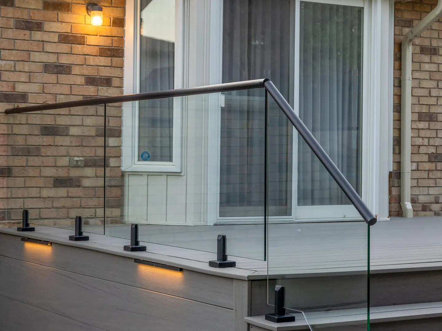 Close-up of a glass panel, spigot and handrail at the corner of a deck